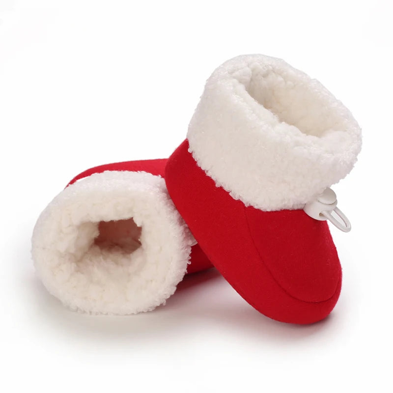 Red baby booties with white fur trim on a white background