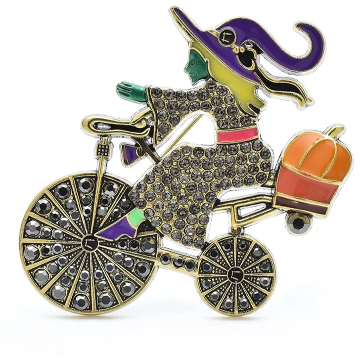 Decorative brooch with a witch riding a bicycle