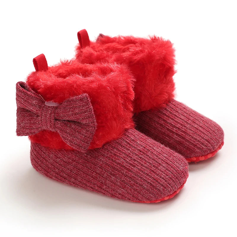 Red baby booties with fluffy texture and a bow on a white background