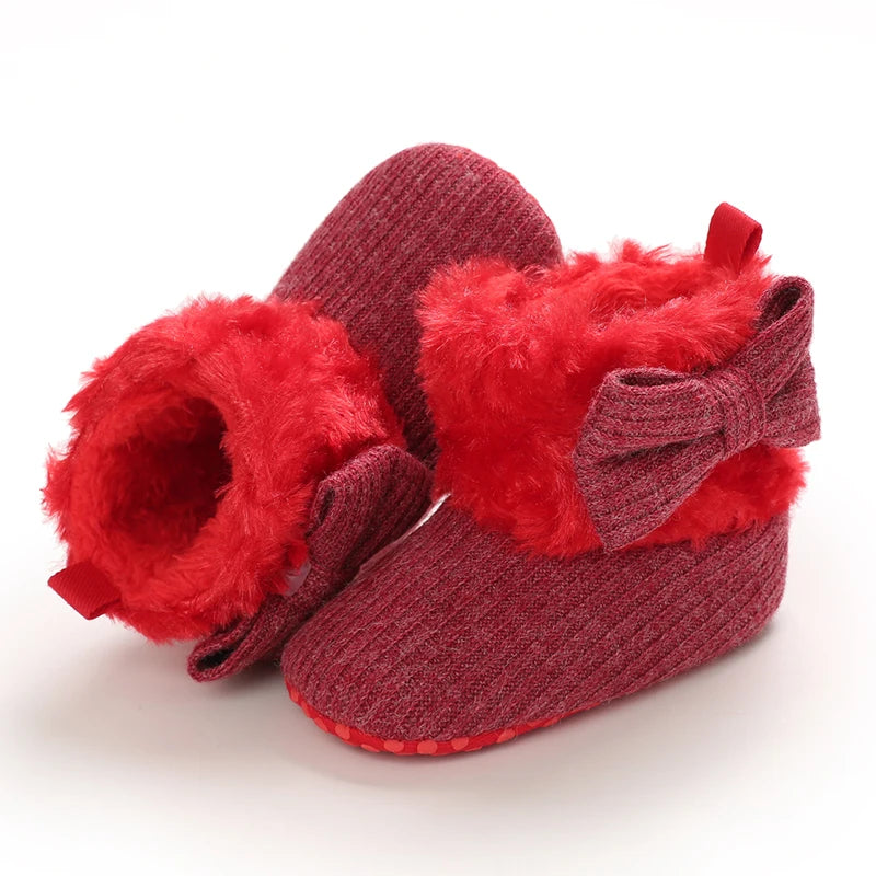 Red baby booties with fluffy texture and a bow on a white background