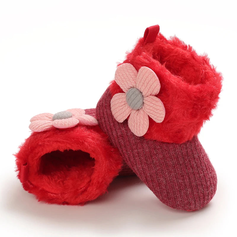 Red baby shoes with pink flower decorations on a white background