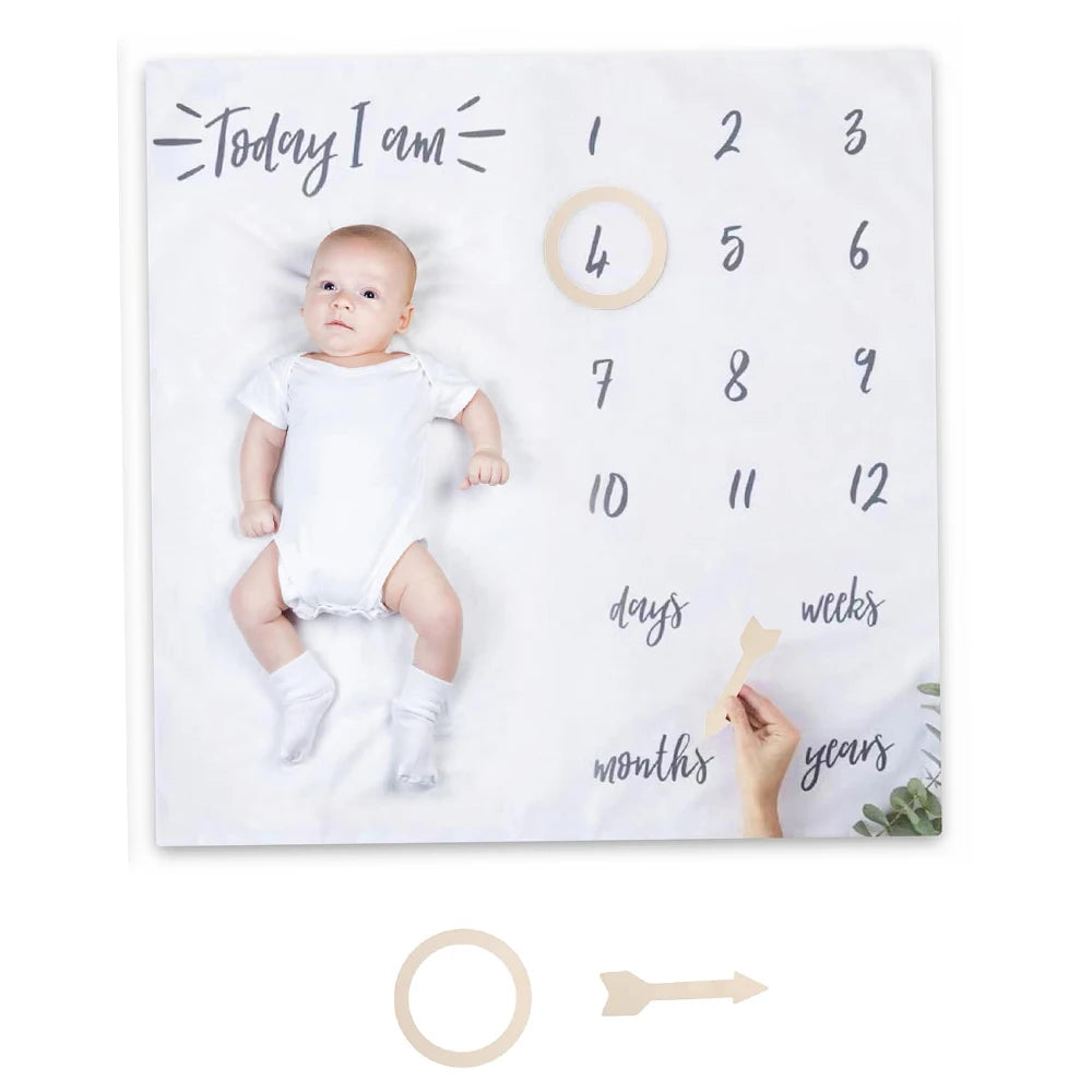 Baby milestone board with baby photo and wooden markers on a white background