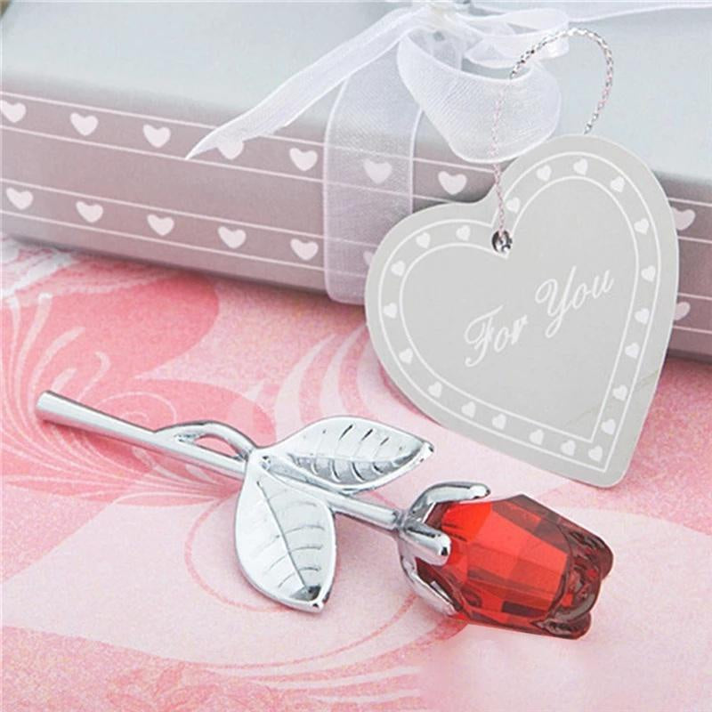 Silver rose with a red gemstone on a pink surface with a heart-shaped 'For You' tag.