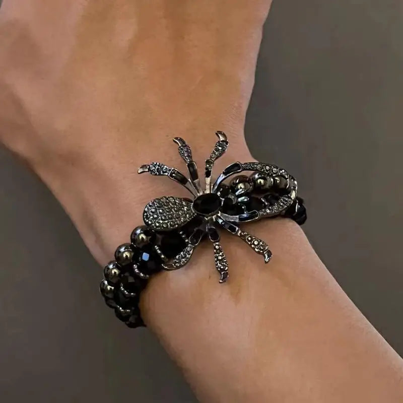Bracelet with spider design on a wrist against a neutral background