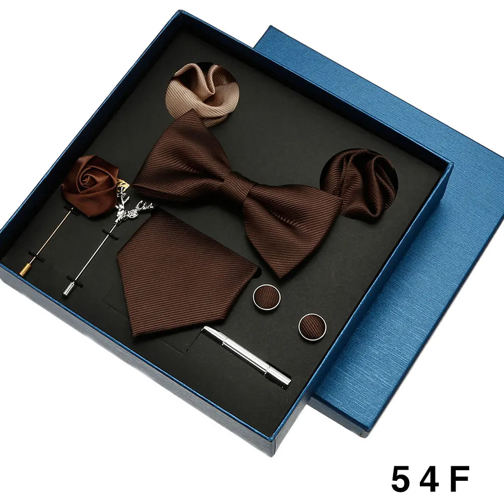 Brown bow tie and pocket square set with accessories in a blue box.