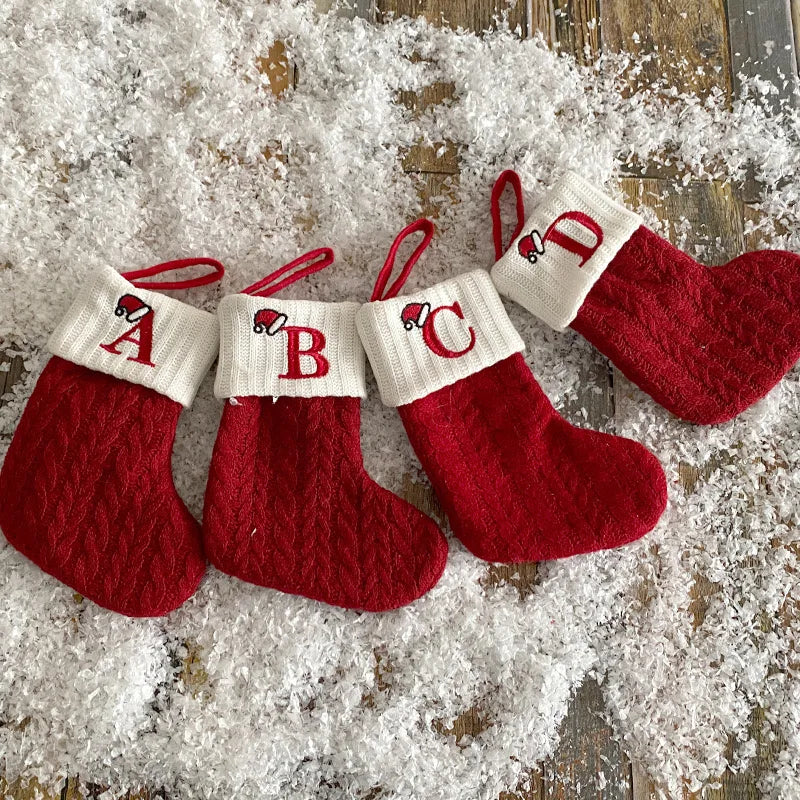 Four red Christmas stockings with white cuffs and lettering on a textured surface.