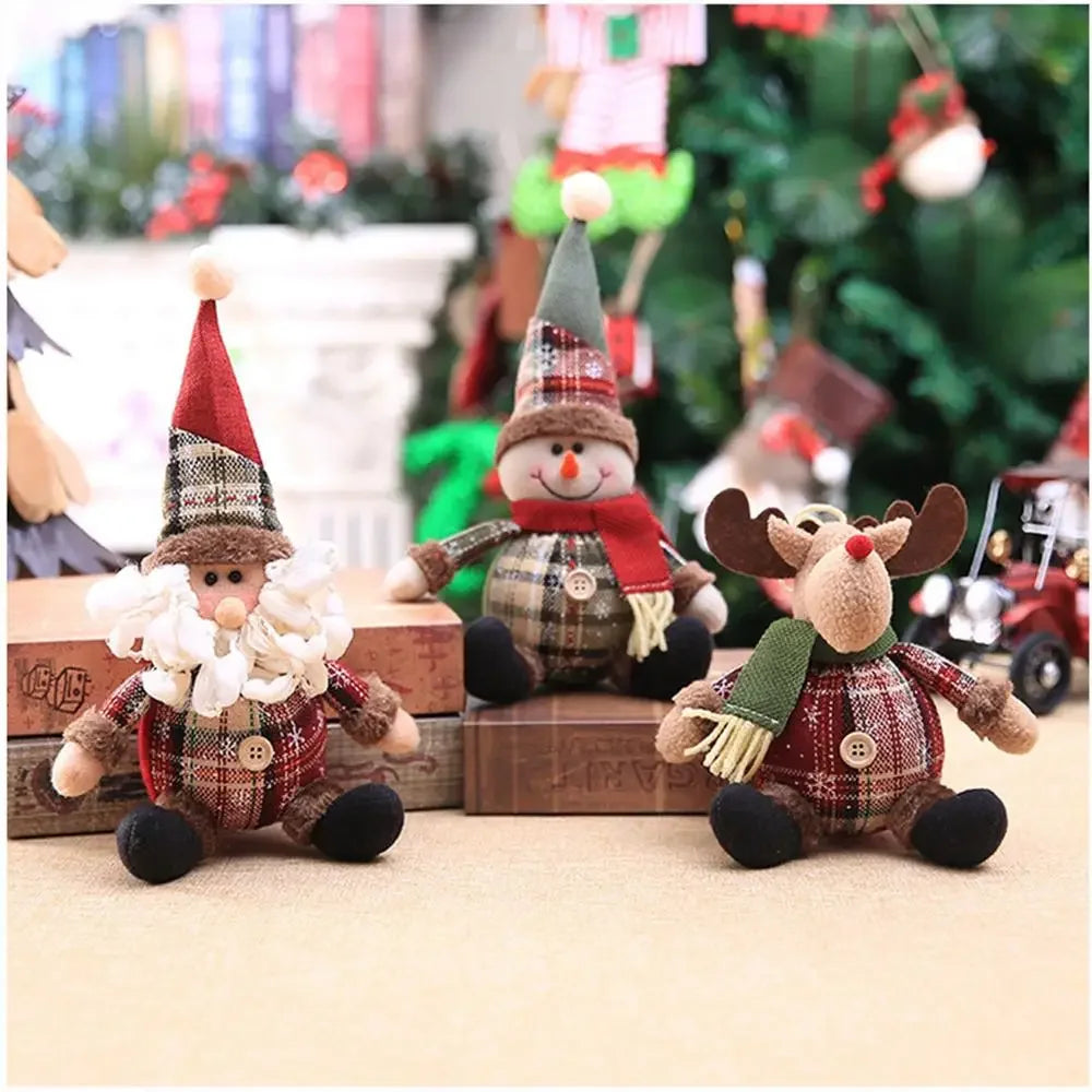 Three Christmas-themed plush toys including a gnome, snowman, and reindeer in front of a decorated Christmas tree.