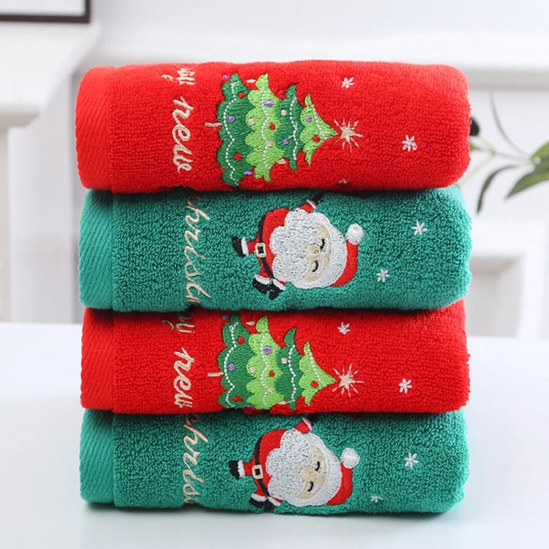 Stack of Christmas-themed towels with Santa Claus and tree designs on a white surface.