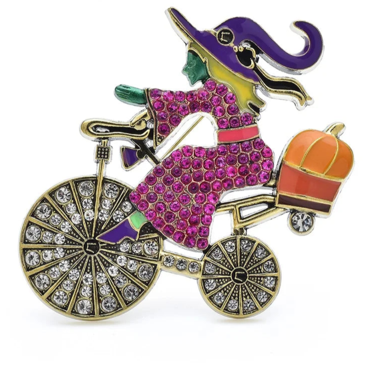 Colorful brooch of a witch on a bicycle with a pumpkin