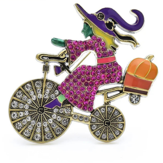 Colorful brooch of a witch on a bicycle with a pumpkin