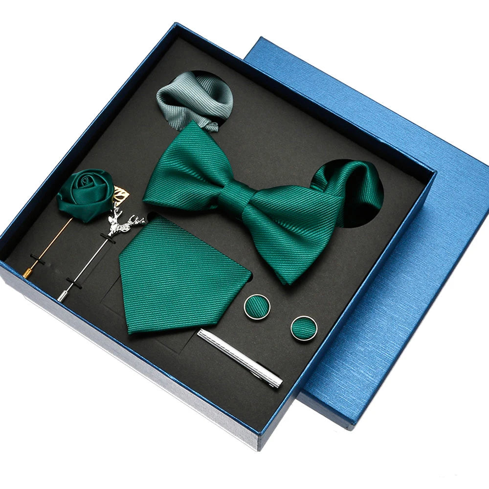Green bow tie and pocket square set with accessories in a blue box on a white background