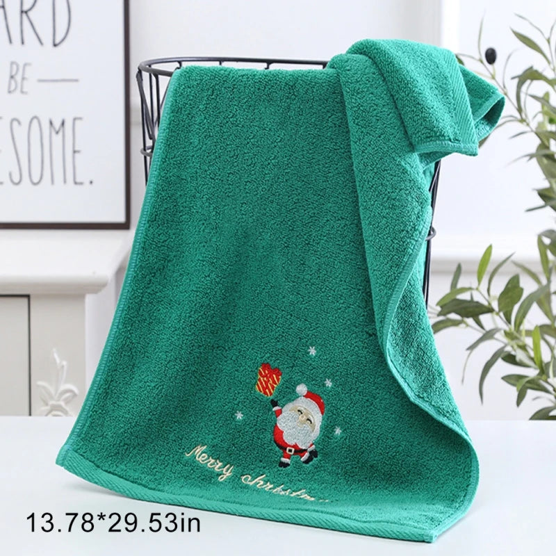 Green towel with embroidered Santa Claus design and 'Merry Christmas' text on a white surface.