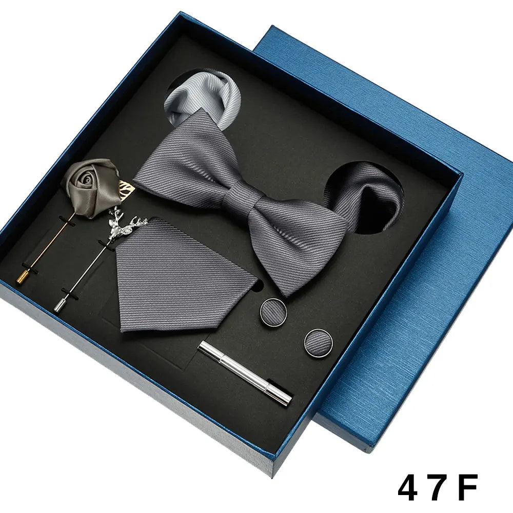 Groomsmen accessories set including bow tie, pocket square, cufflinks, and tie clip in a blue box.