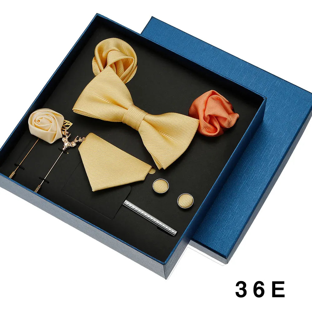 Groomsmen accessories set including bow tie, pocket square, cufflinks, and tie clip in a blue box.