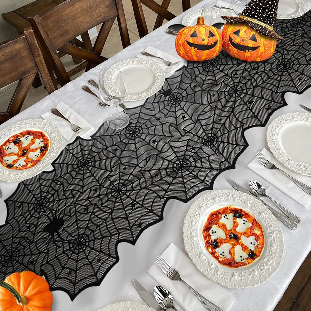 Halloween-themed table setting with spider web table runner, pumpkins, and ghost pizzas.
