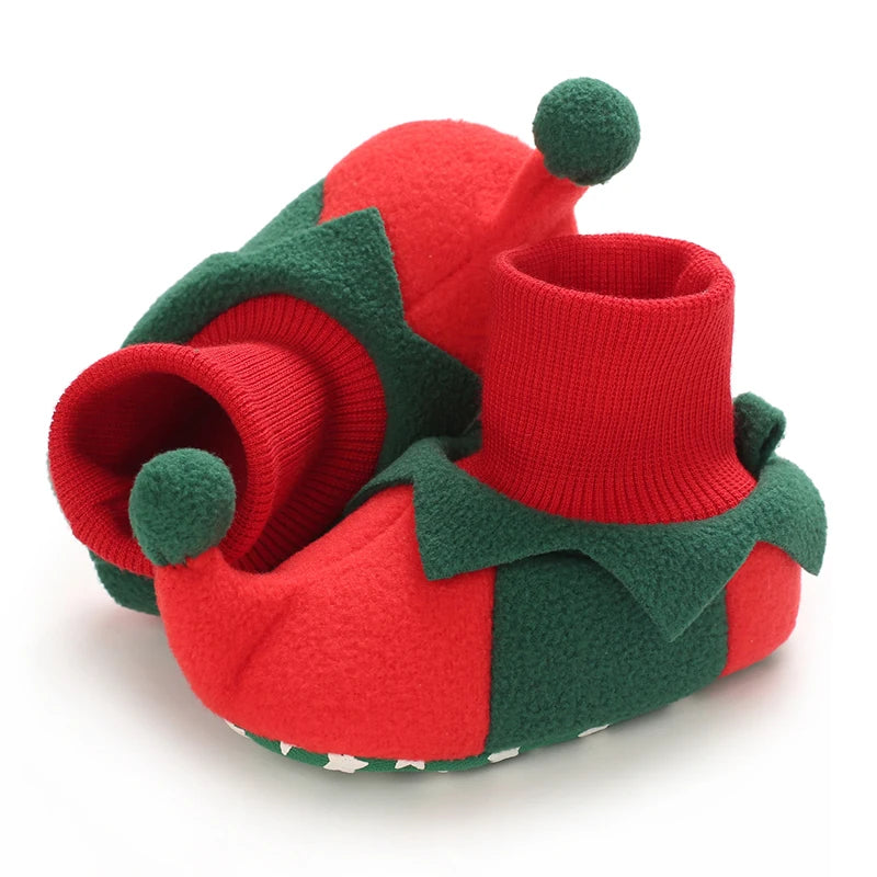 Red and green baby booties with pom-pom details on a white background