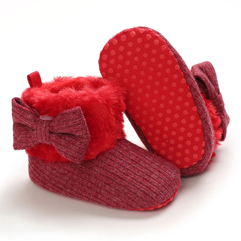 Red baby booties with a bow on a white background