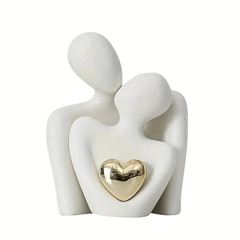 Sculpture of two figures embracing with a gold heart detail on a white background