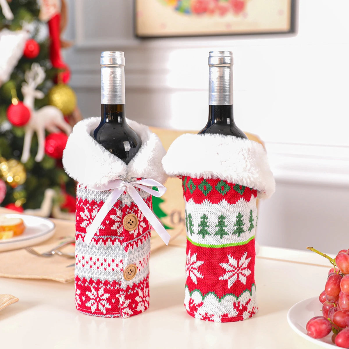 Two wine bottles wrapped in festive Christmas-themed covers on a table with a decorated Christmas tree in the background.