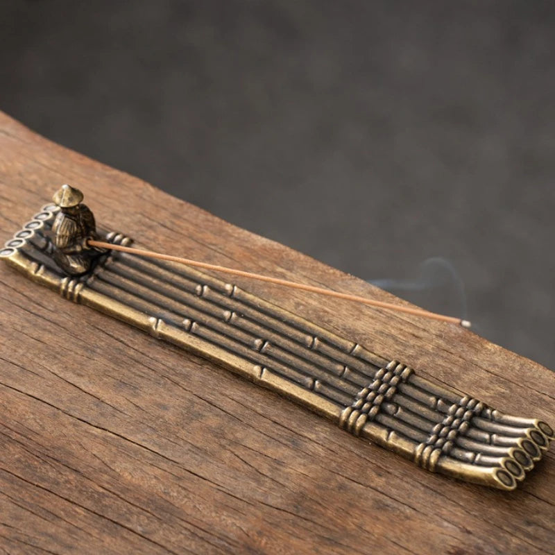 Bronze incense burner with sticks on a wooden surface