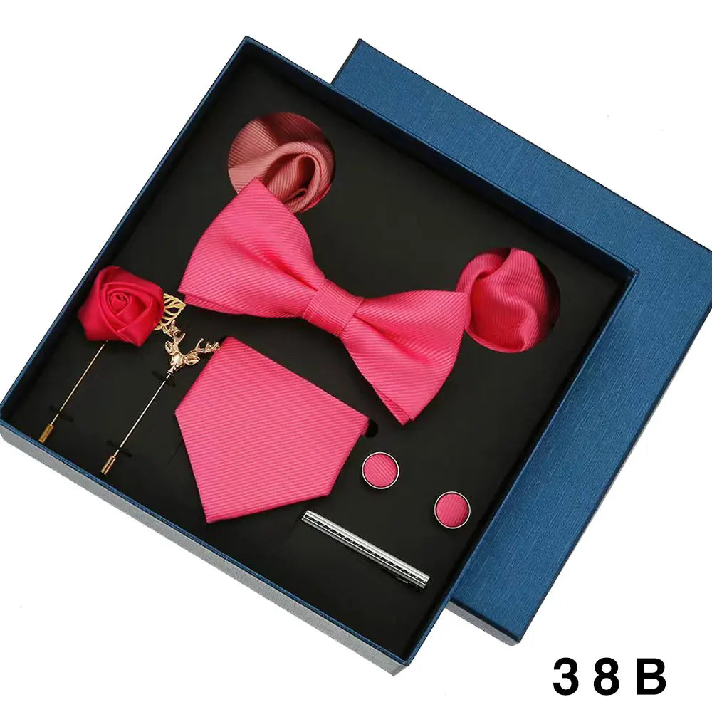 Pink bow tie and pocket square set with accessories in a blue box.