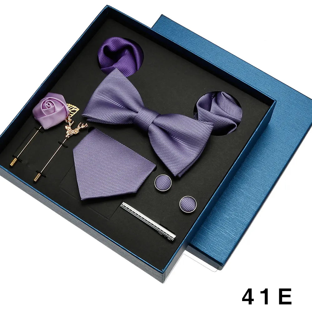 Purple bow tie and pocket square set with accessories in a blue box.