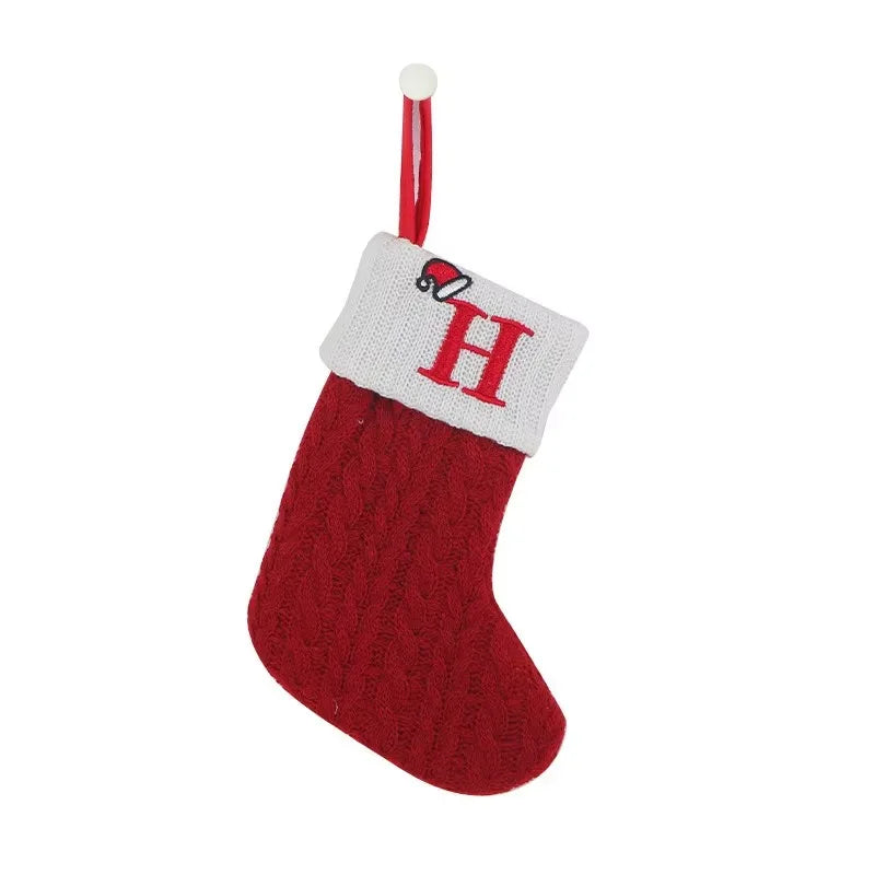 Red Christmas stocking with white cuff featuring a letter 'H' on a white background