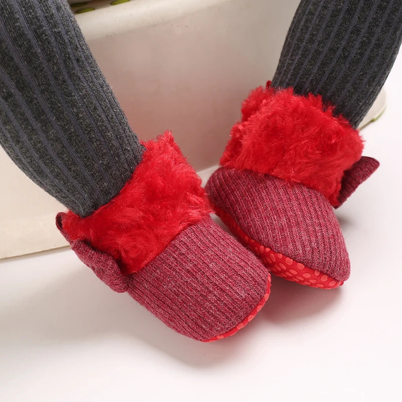 Red baby booties with fluffy cuffs on a white background