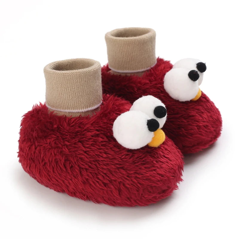 Red fuzzy baby booties with character face design on a white background