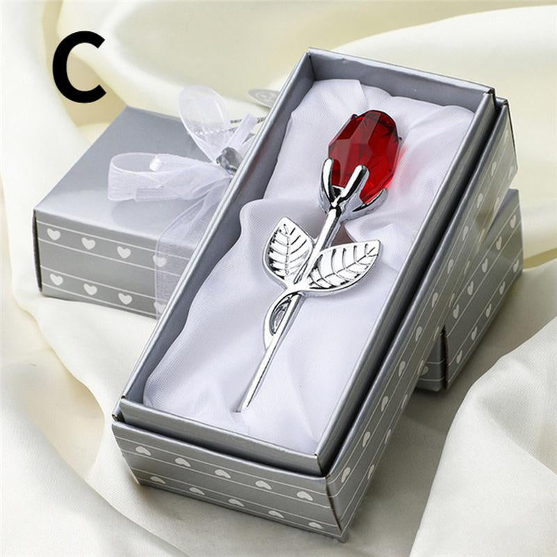 Silver rose with a red gemstone in a decorative box.