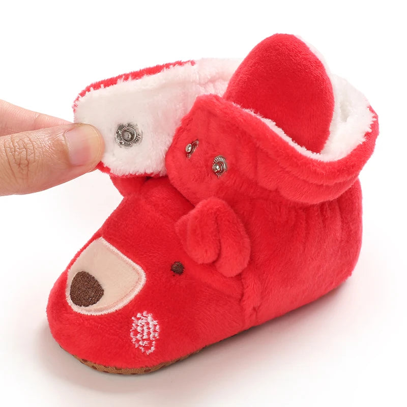 Red baby bootie with a white interior, held by a hand on a white background