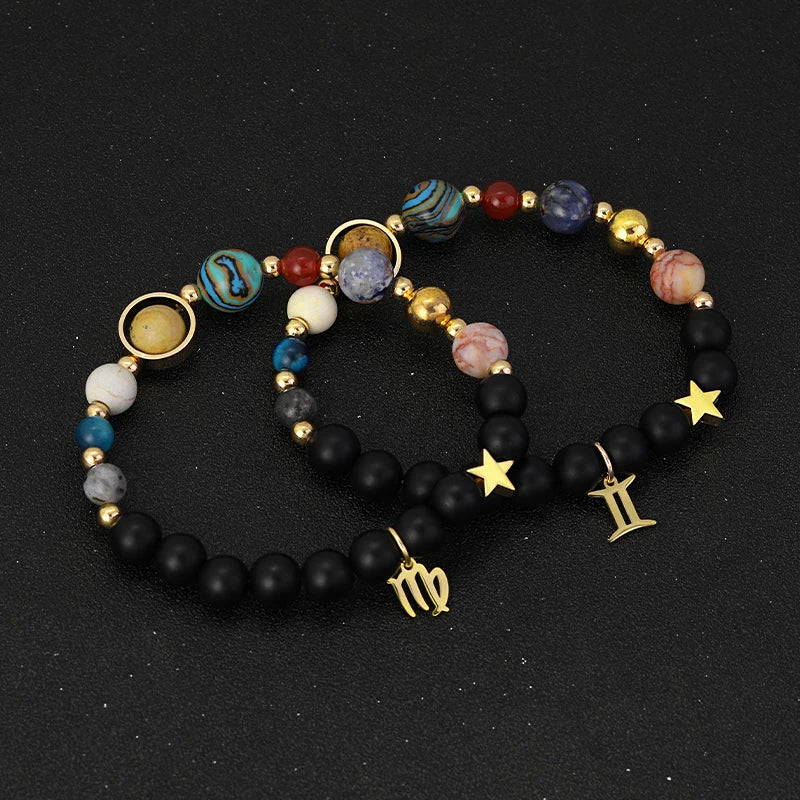 Set of two beaded bracelets with star, moon, and zodiac symbol charms on a black background
