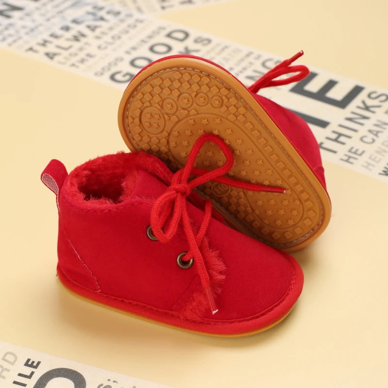Red baby boots with brown soles on a newspaper background