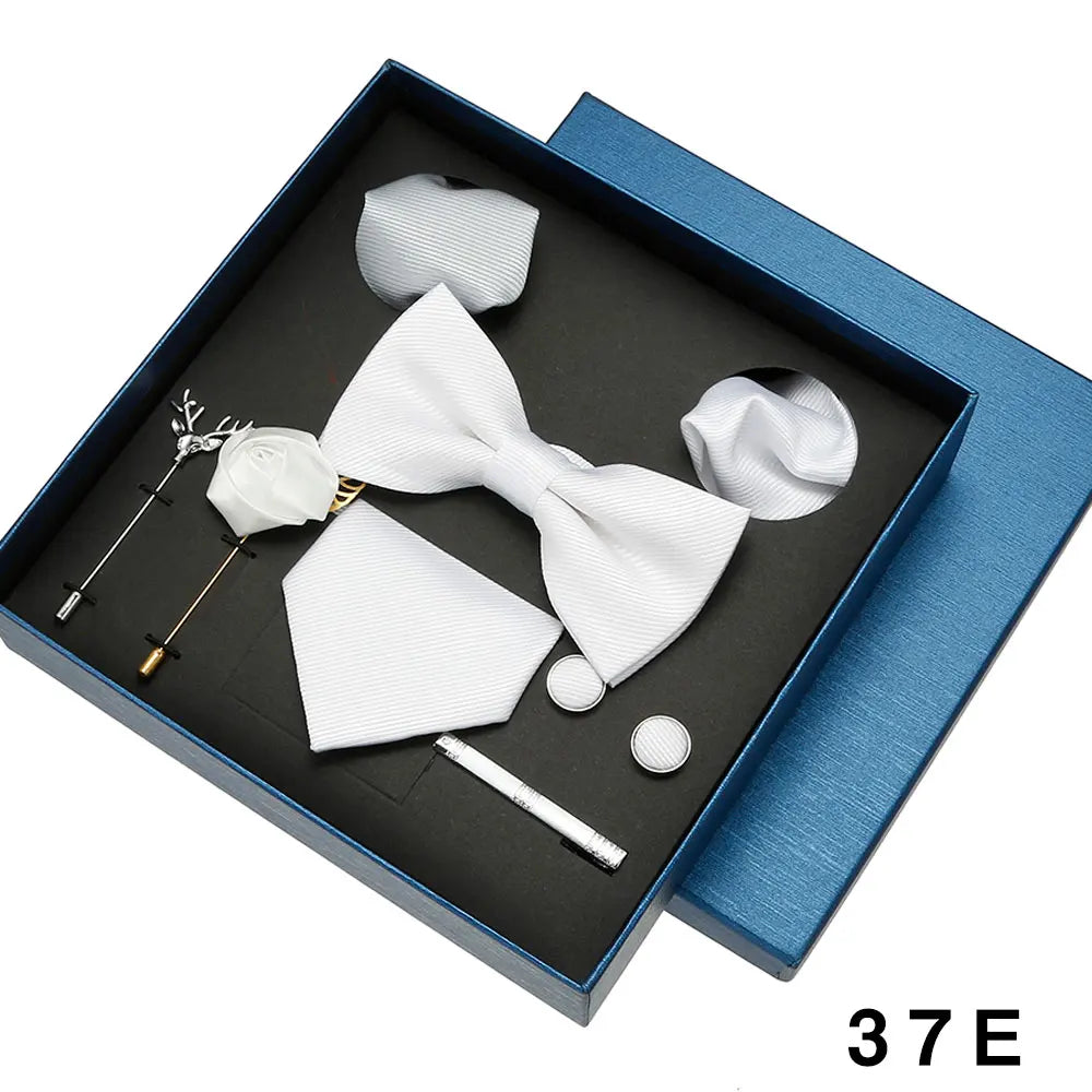 White bow tie and pocket square set with accessories in a blue box.