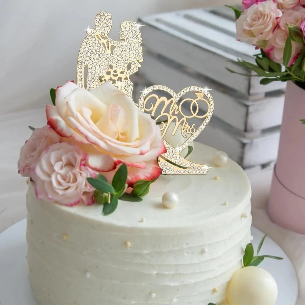 White cake with pink roses and a 'Mr & Mrs' topper on a light background