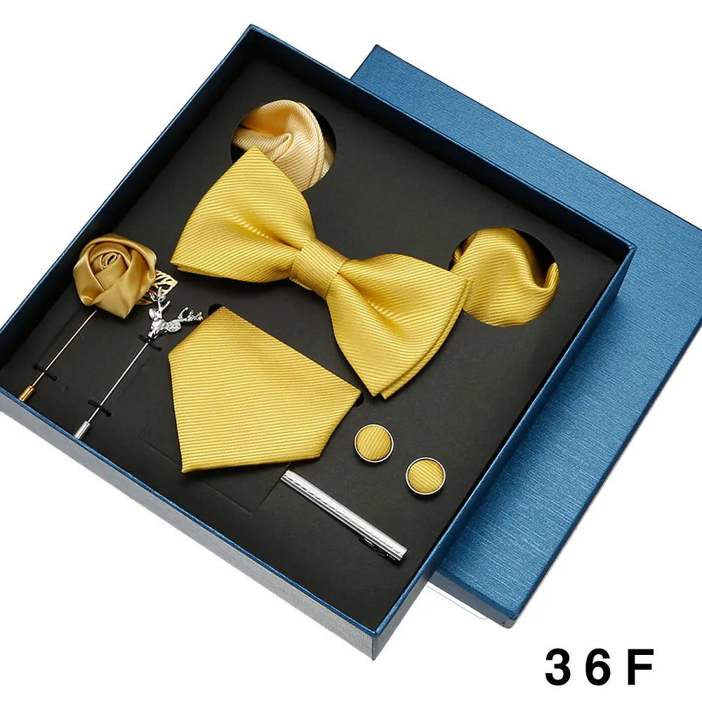 Yellow bow tie and pocket square set with accessories in a blue box.