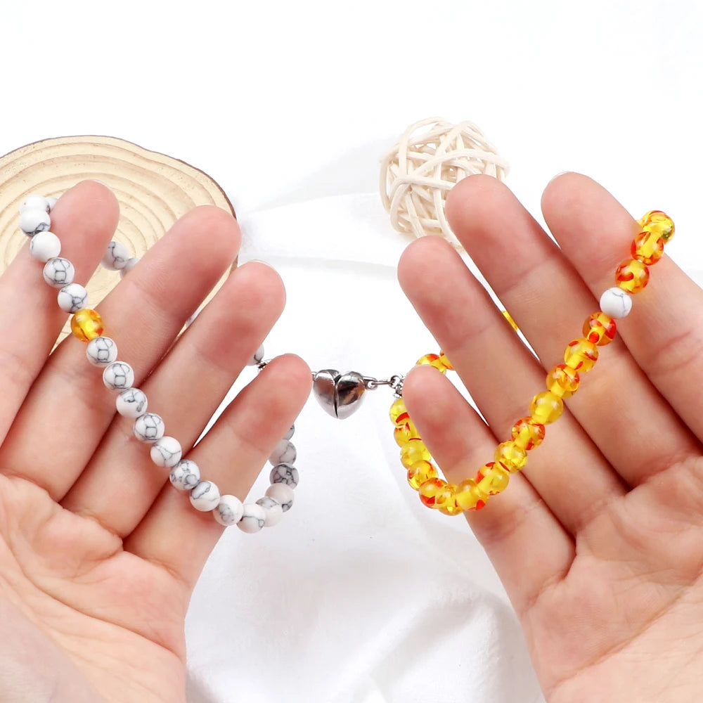 Two hands holding colorful beaded bracelets on a white background