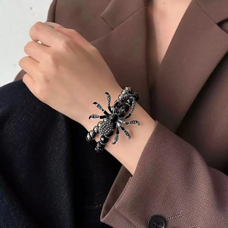 Person wearing a spider-shaped bracelet on a plain background