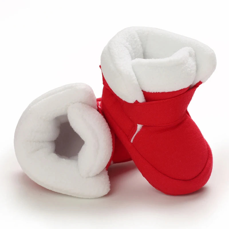 Red baby booties with white fur trim on a white background